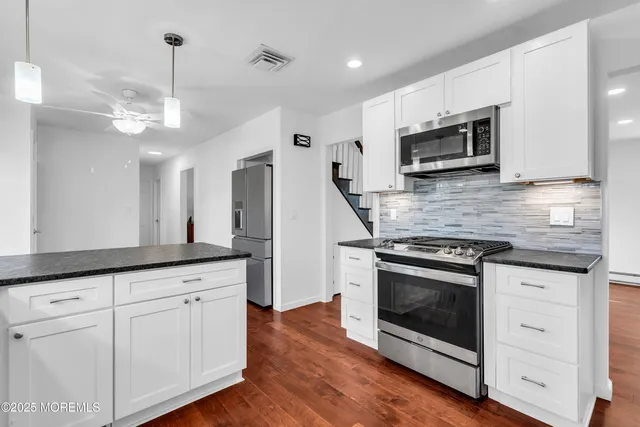 a kitchen with stainless steel appliances granite countertop white cabinets and a window