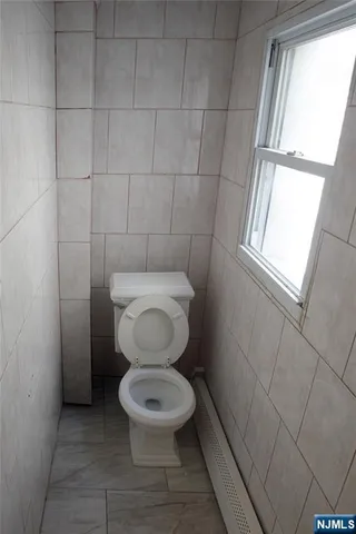 a white toilet sitting in a bathroom next to a window