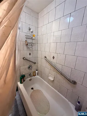a bathroom with a white tub shower vanity and sink