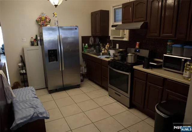 a kitchen with stainless steel appliances granite countertop a refrigerator a stove and a sink