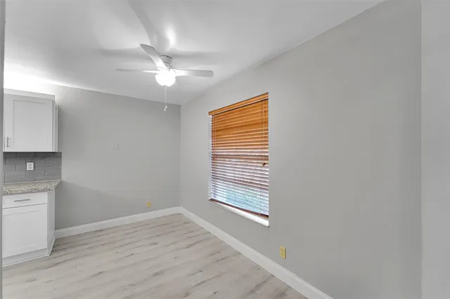 a view of an empty room with a window and wooden floor