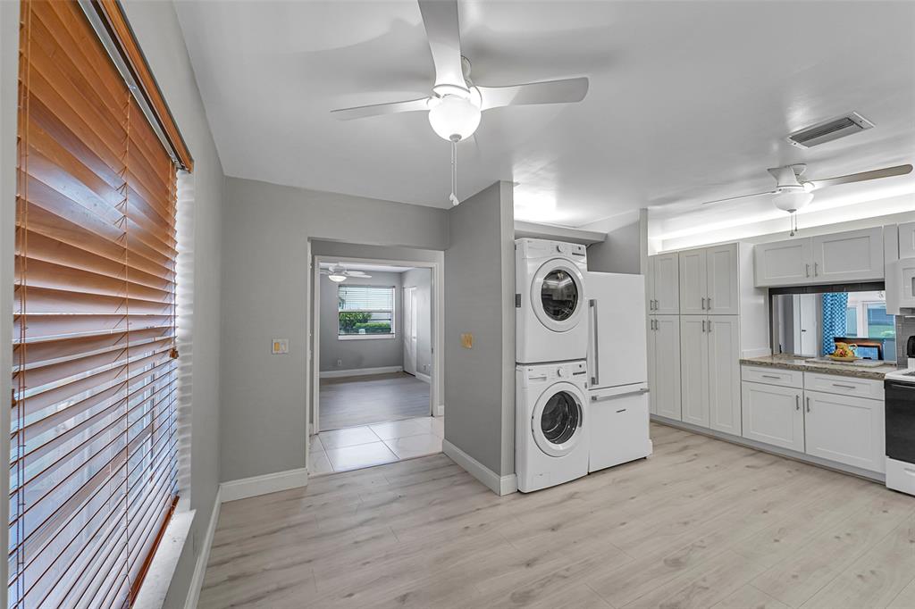 1521 Northwest 19th Terrace, Unit 101 Delray Beach, FL 33445 - Photo 12 of 42 a view of a kitchen with a sink and dishwasher white cabinets with wooden floor