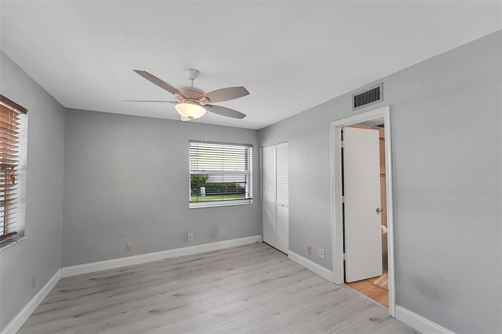 1521 Northwest 19th Terrace, Unit 101 Delray Beach, FL 33445 - Photo 6 of 42 an empty room with wooden floor and windows