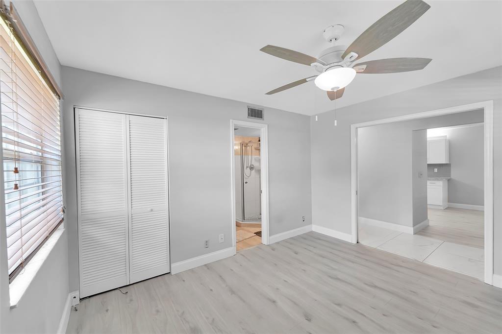1521 Northwest 19th Terrace, Unit 101 Delray Beach, FL 33445 - Photo 7 of 42 a view of an empty room with wooden floor and a window