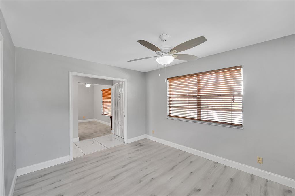 1521 Northwest 19th Terrace, Unit 101 Delray Beach, FL 33445 - Photo 8 of 42 a view of an empty room with wooden floor and a window