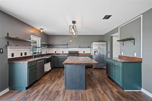 a kitchen with kitchen island wooden floors stainless steel appliances a sink and cabinets