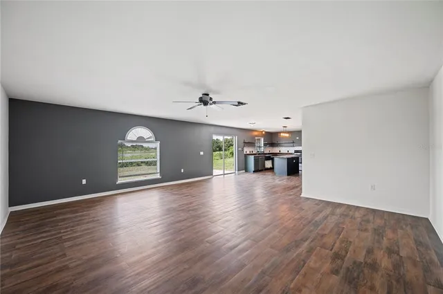an empty room with wooden floor cabinet and windows