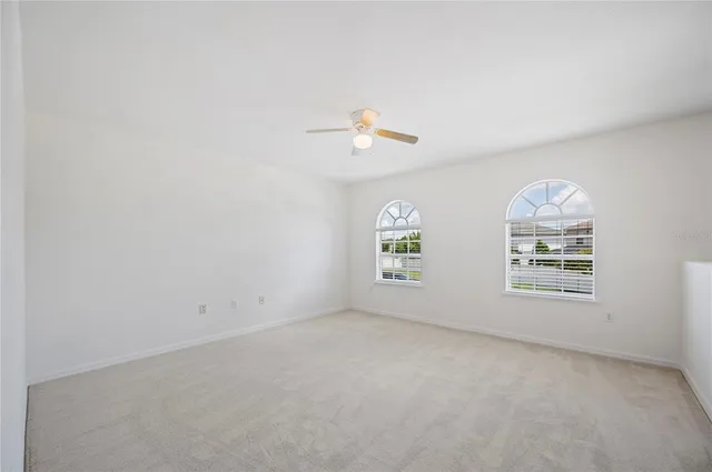 an empty room with windows and ceiling fan