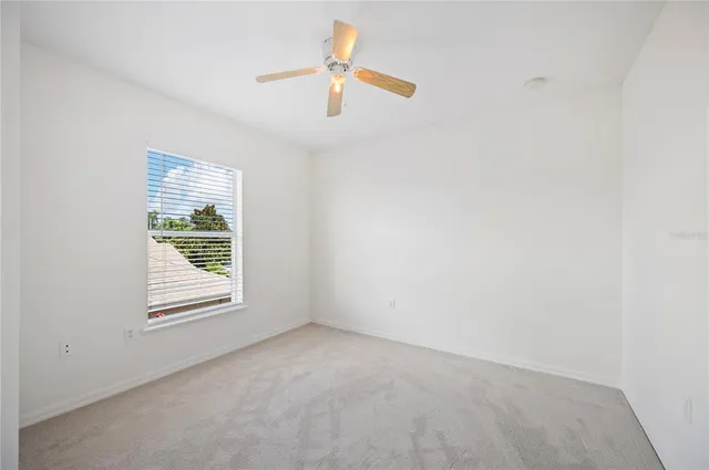 an empty room with a window and a ceiling fan