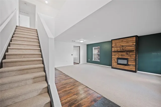a view of an empty room with stairs and a fireplace