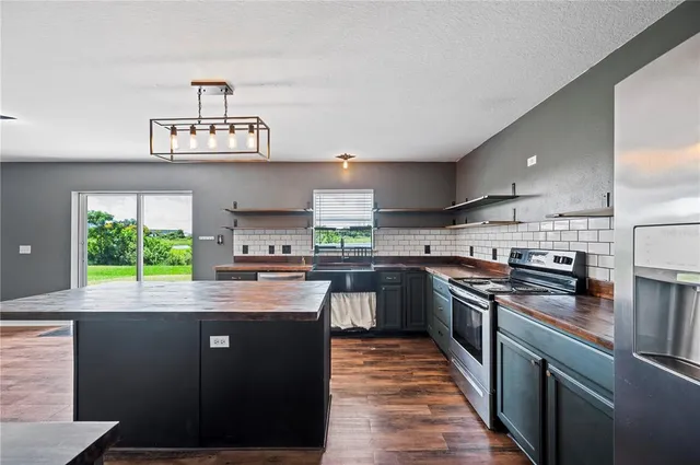 a kitchen with stainless steel appliances granite countertop a sink a stove and a refrigerator