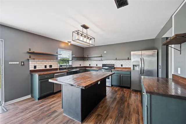 a kitchen with stainless steel appliances granite countertop a stove a sink dishwasher and a refrigerator