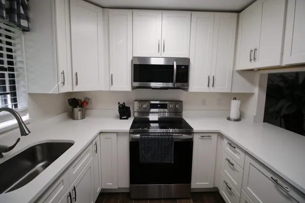 a kitchen with white cabinets and black appliances