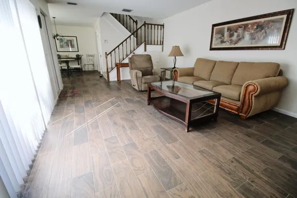a living room with couches and a dining table with wooden floor