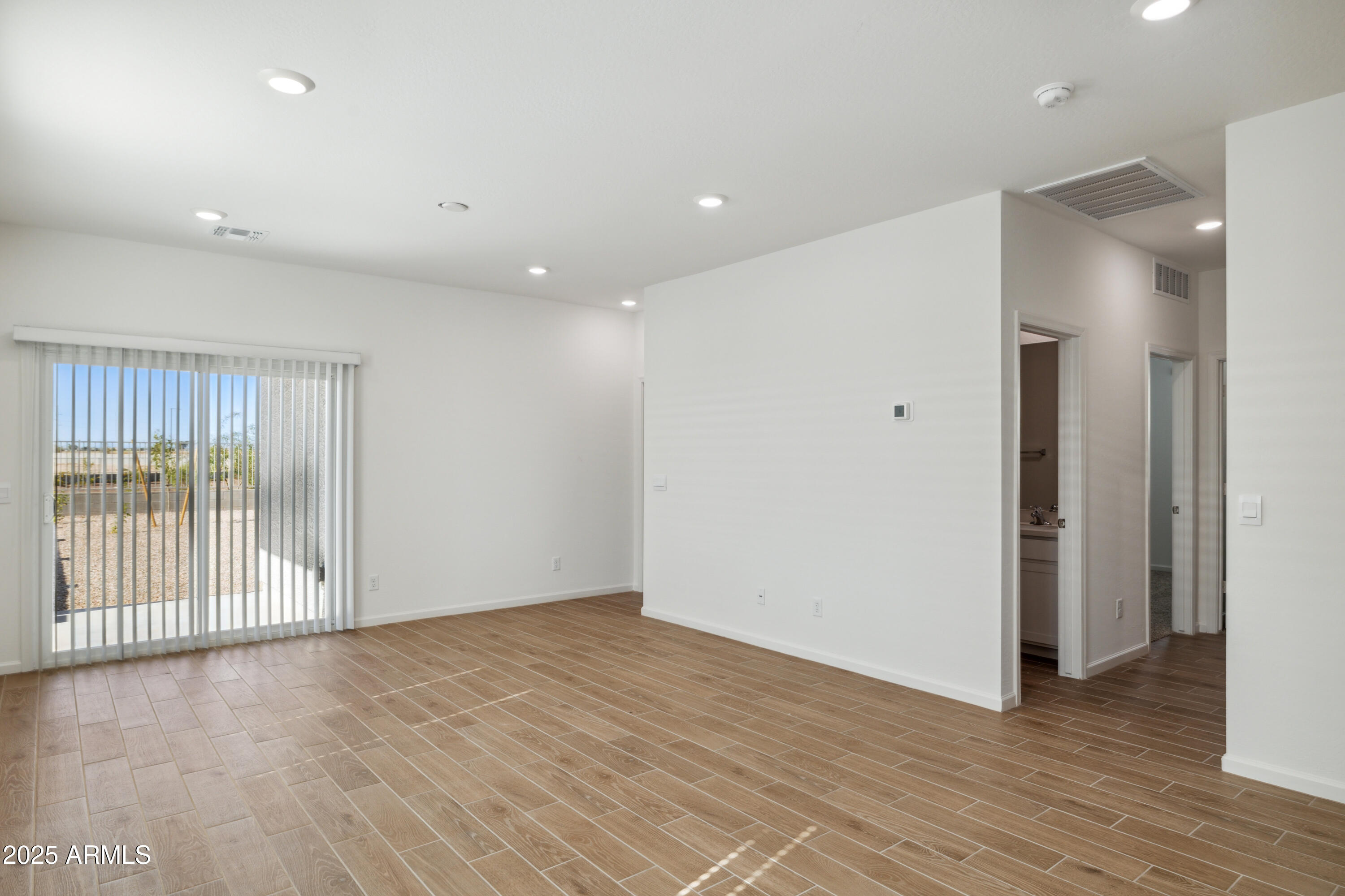 25470 West Fraktur Road Buckeye, AZ 85326 - Photo 3 of 12 an empty room with wooden floor and windows