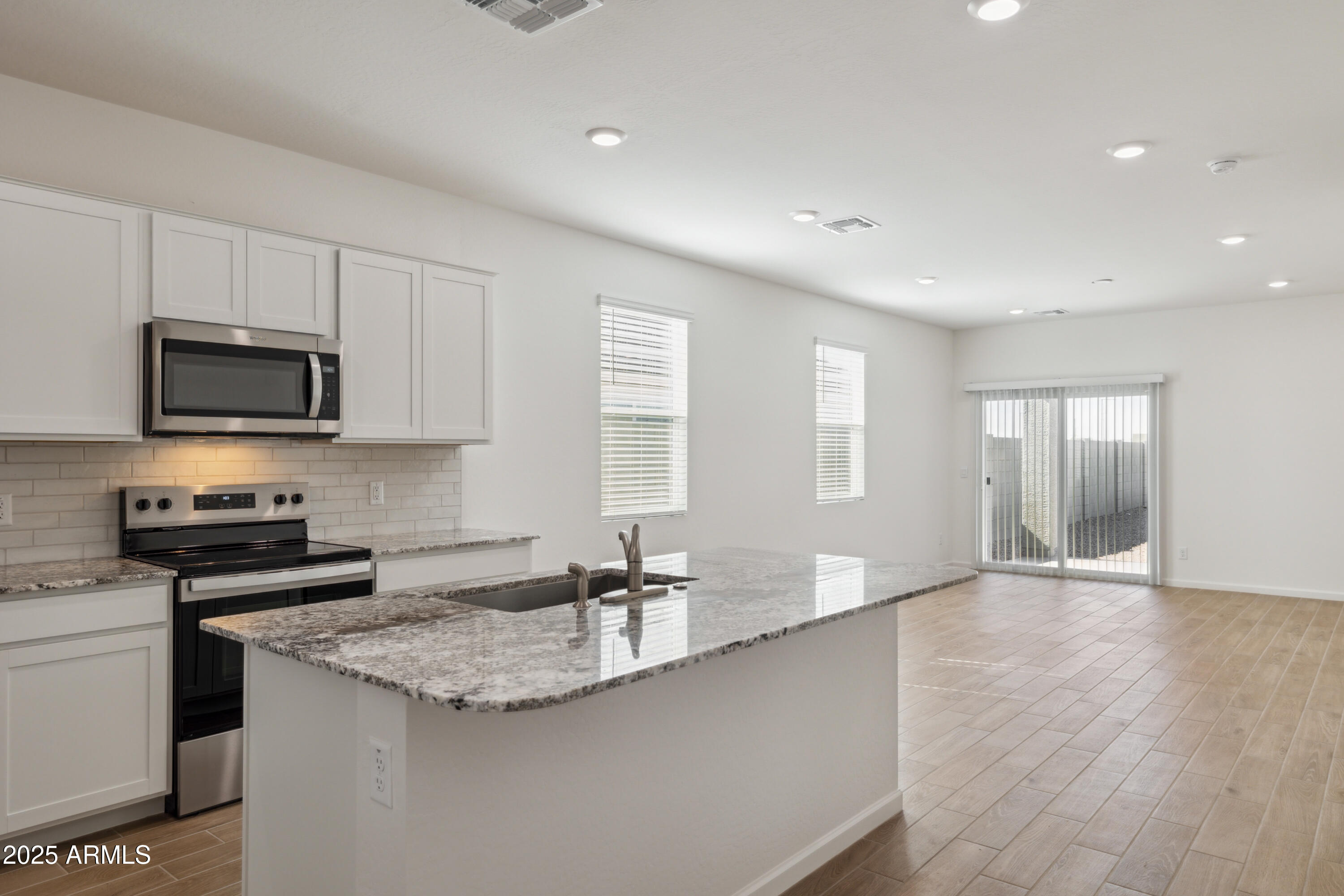 25470 West Fraktur Road Buckeye, AZ 85326 - Photo 4 of 12 a kitchen with granite countertop a sink and a stove top oven with wooden floor