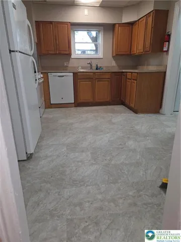 a kitchen with granite countertop a refrigerator and wooden cabinets
