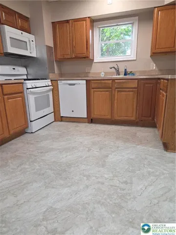 a kitchen with granite countertop a sink cabinets stainless steel appliances and a window