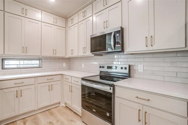 a kitchen with white cabinets and appliances