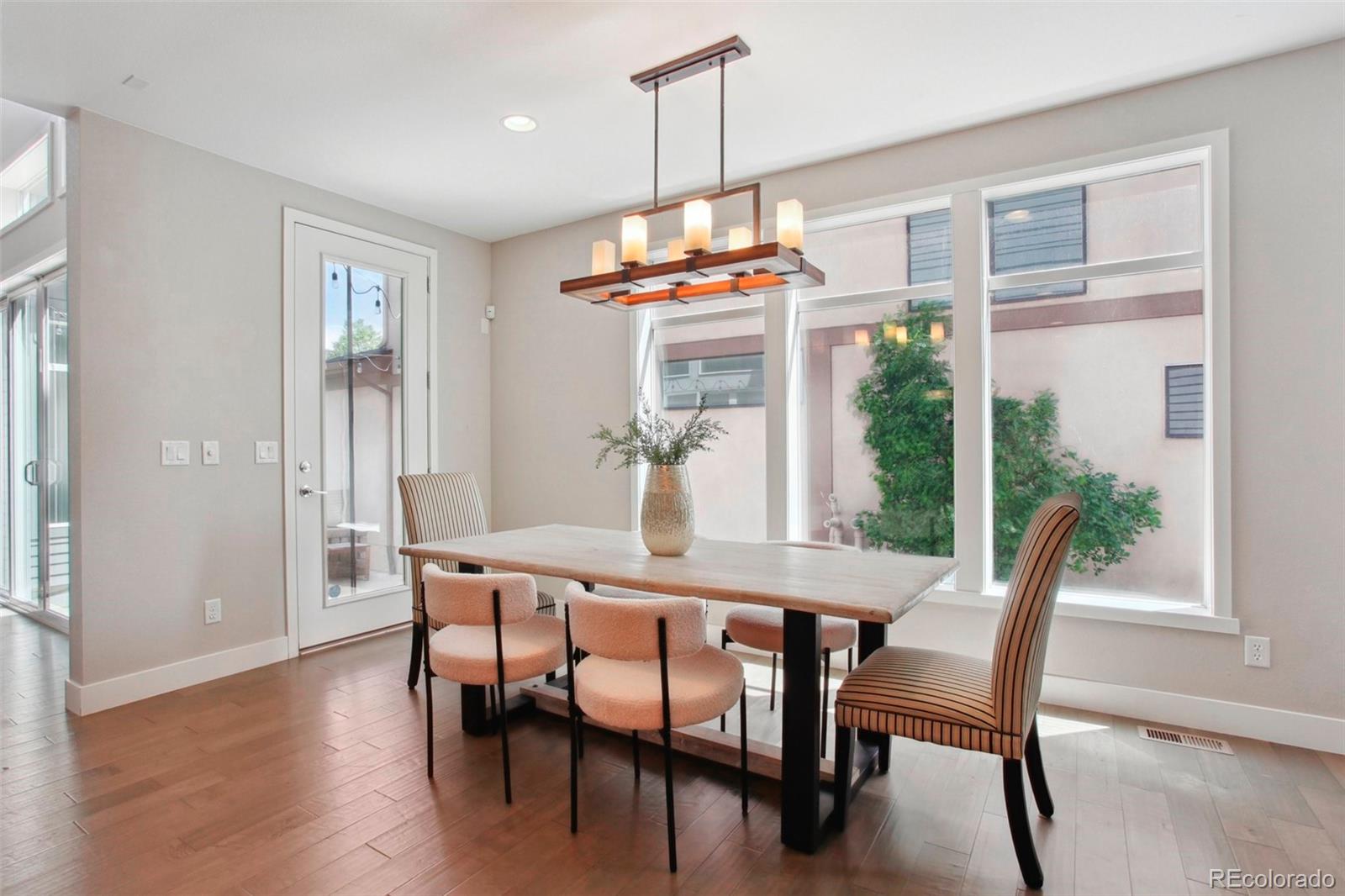 6735 Avrum Drive Denver, CO 80221 - Photo 6 of 29 a dining room with wooden floor a chandelier a glass table and chairs