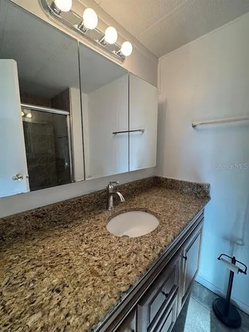 a bathroom with a granite countertop sink a toilet and a mirror