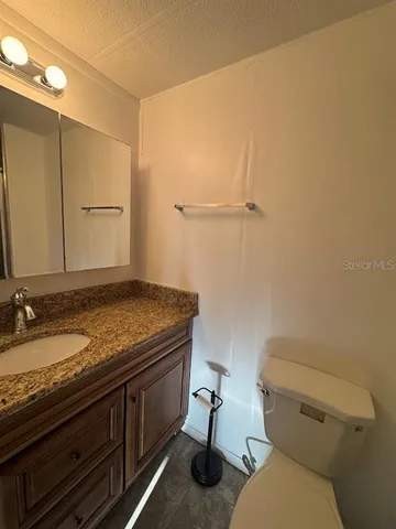 a bathroom with a granite countertop toilet sink and mirror