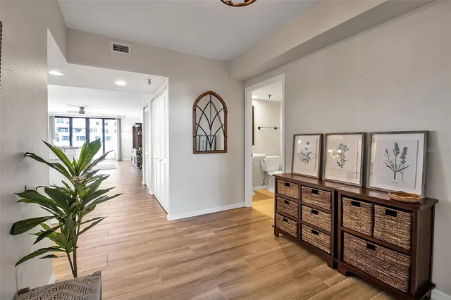 a view of a hallway with wooden floor and paintings on the wall