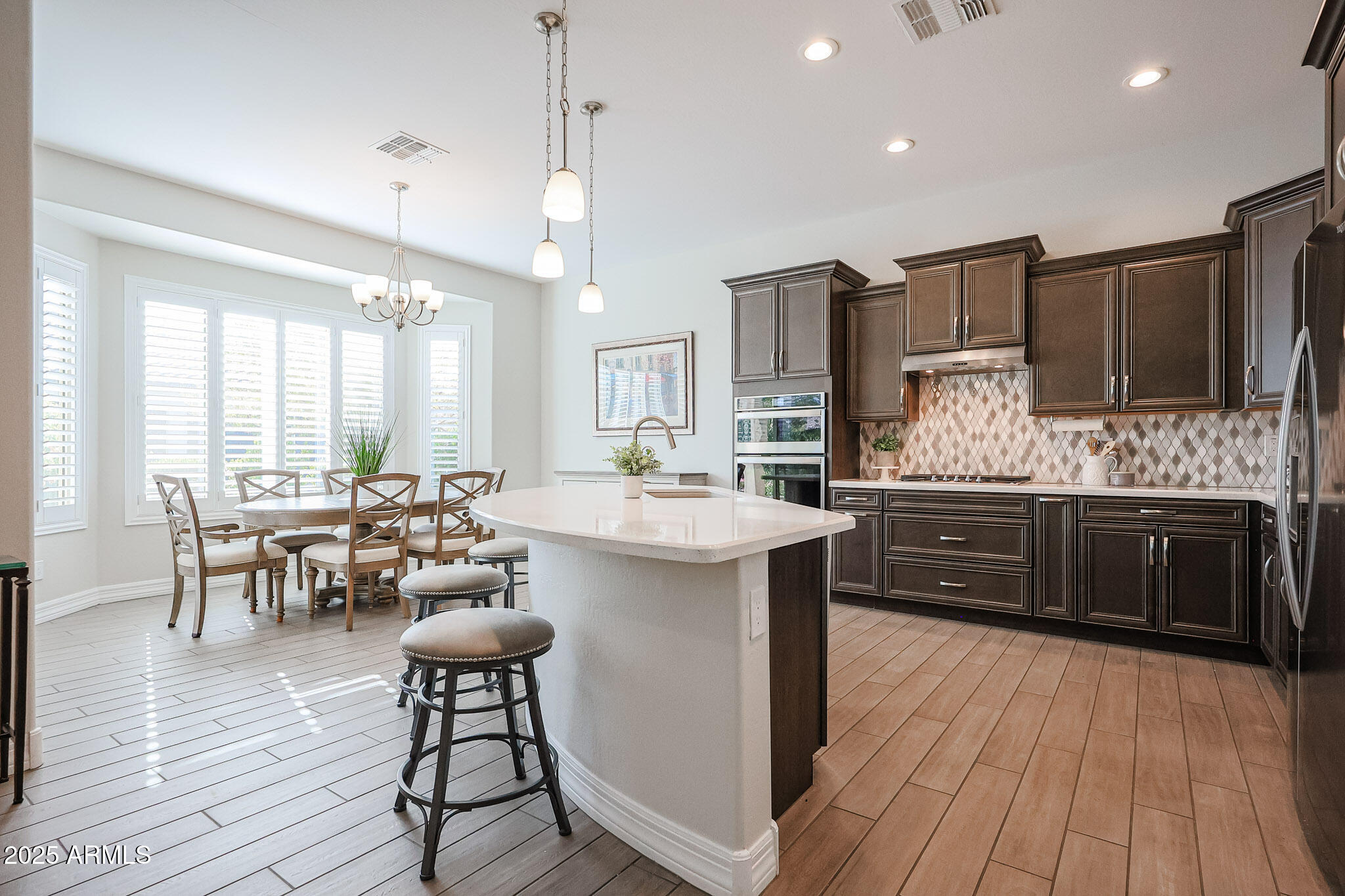 17885 West Ashurst Drive Goodyear, AZ 85338 - Photo 6 of 63 a kitchen with stainless steel appliances kitchen island granite countertop a table chairs sink and cabinets