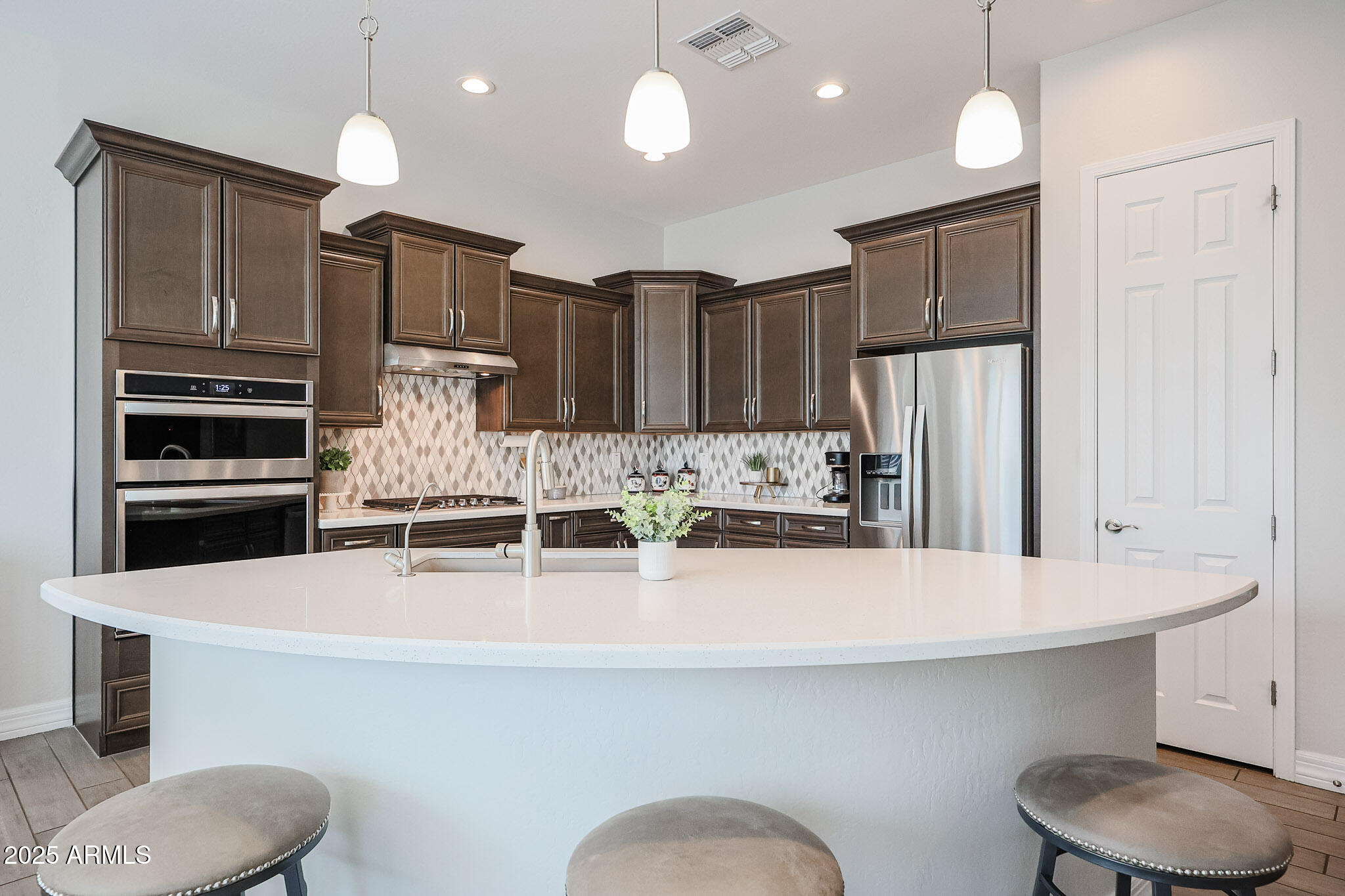 17885 West Ashurst Drive Goodyear, AZ 85338 - Photo 7 of 63 a kitchen with stainless steel appliances kitchen island granite countertop a refrigerator a sink and chairs