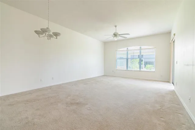 an empty room with windows and ceiling fan