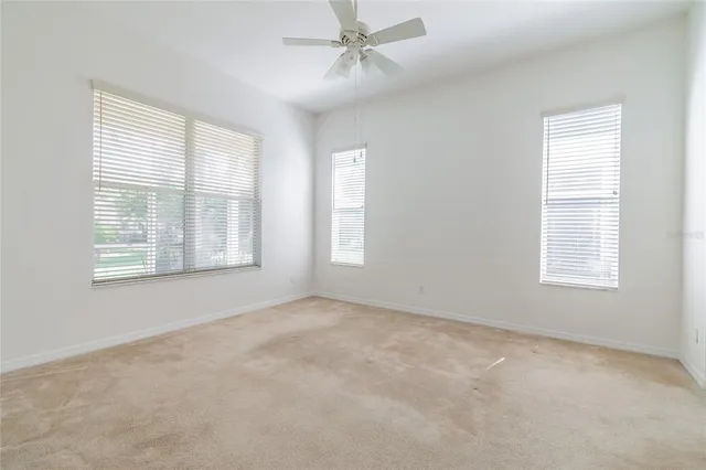 an empty room with windows and fan