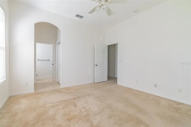 an empty room with a chandelier fan and windows