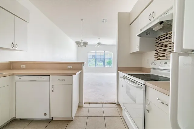 a kitchen with granite countertop white cabinets and white appliances