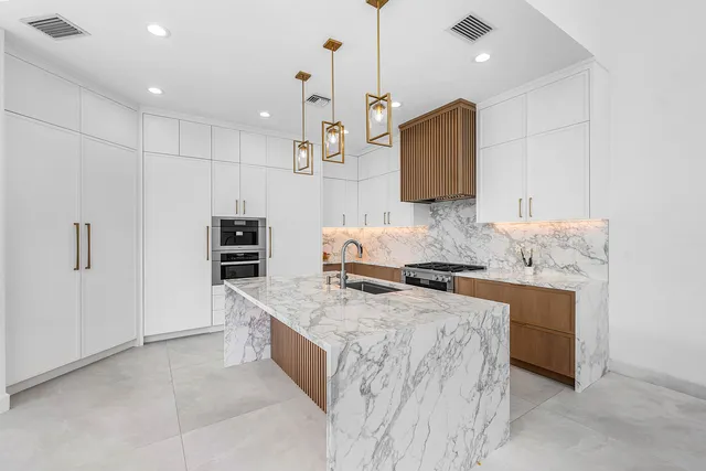 a large white kitchen with stainless steel appliances kitchen island a stove a sink a refrigerator and a cabinets