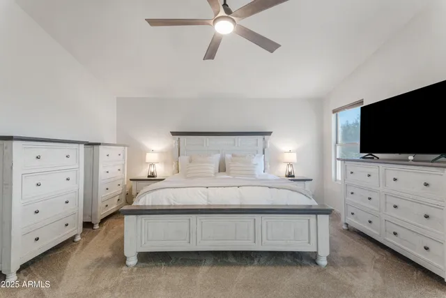 a bedroom with a bed and a flat tv screen on dresser