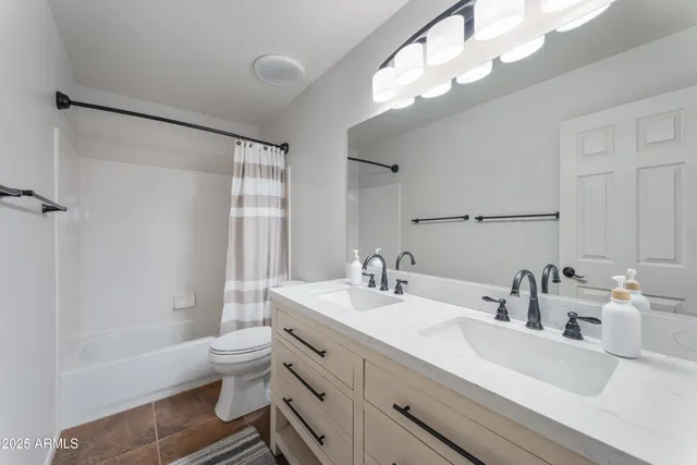 a bathroom with a bathtub shower sink vanity mirror and toilet