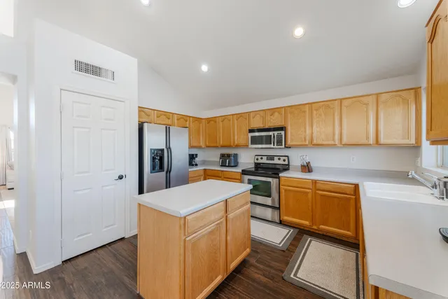 a kitchen with stainless steel appliances granite countertop a refrigerator a sink dishwasher a stove with wooden cabinets and floor