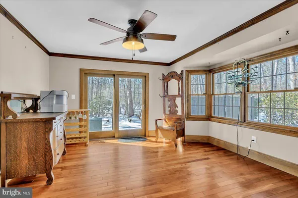 a view of a livingroom with furniture hardwood floor a ceiling fan and windows