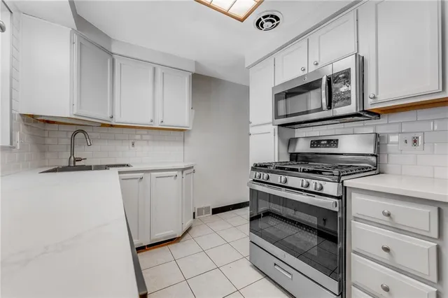 a kitchen with white cabinets and appliances