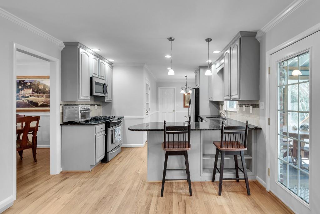1440 Diamond Head Circle Decatur, GA 30033 - Photo 13 of 35 a kitchen with stainless steel appliances kitchen island granite countertop a stove a refrigerator a sink a dining table and chairs with wooden floor