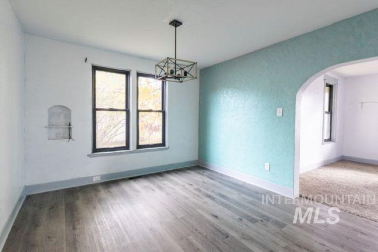 622 West Commercial Street Weiser, ID 83672 - Photo 8 of 21 Empty room with arched walkways, a chandelier, and light wood-style floors