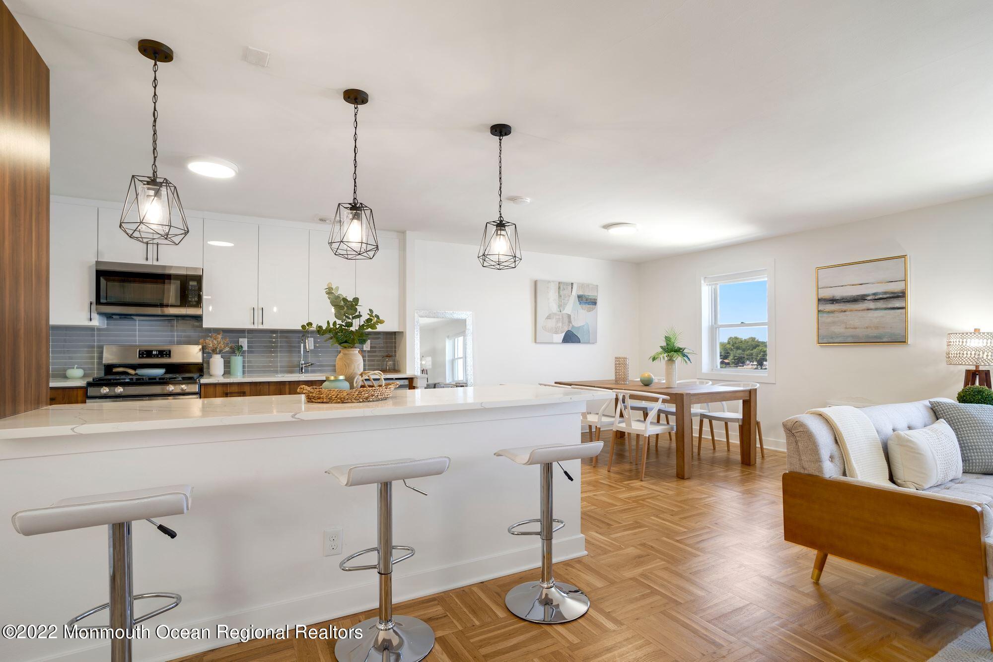 122 Bodman Place, Unit 6B Red Bank, NJ 07701 - Photo 19 of 30 a kitchen with stainless steel appliances granite countertop a stove top oven a refrigerator a sink dishwasher a dining table and chairs with wooden floor