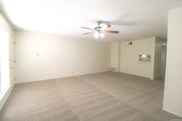 an empty room with chandelier fan and ceiling fan
