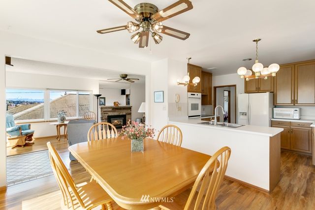 a dining room with wooden floor a chandelier a glass table and chairs