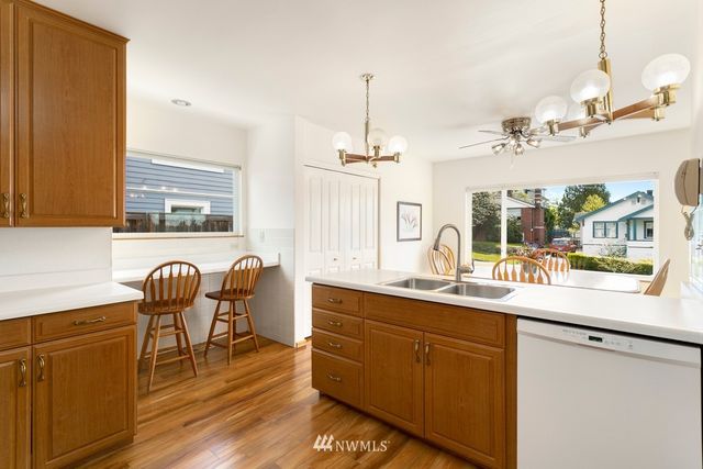 a dining hall with stainless steel appliances granite countertop a sink a stove a dining table and chairs with wooden floor