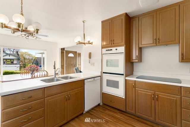 a kitchen with a sink dishwasher and white cabinets with wooden floor