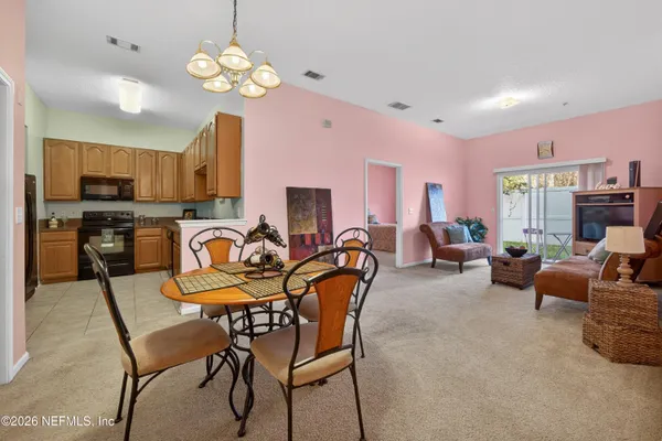 a view of a dining room with furniture a chandelier and a window