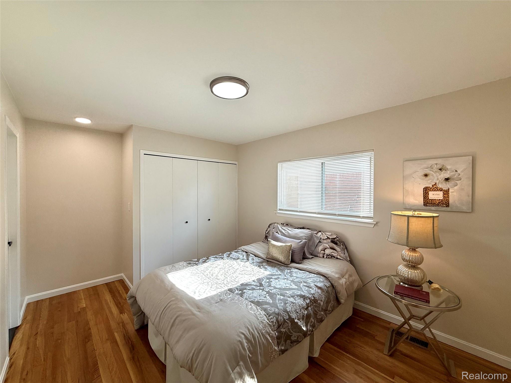 39909 Lynn Street Canton, MI 48187 - Photo 27 of 45 Bedroom featuring wood-finish flooring, a window with horizontal blinds, and a built-in closet with bi-fold doors
