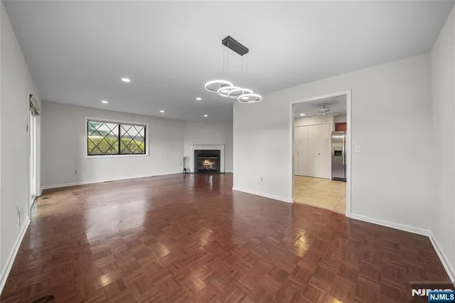 a view of an empty room with window and wooden floor