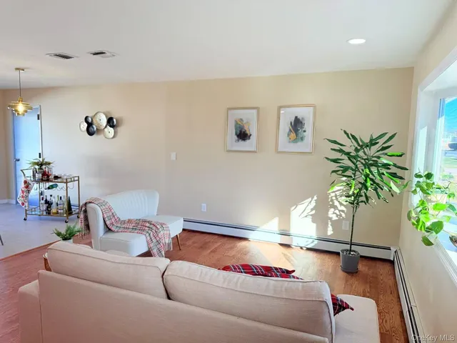a view of a dining room with furniture a potted plant and wooden floor